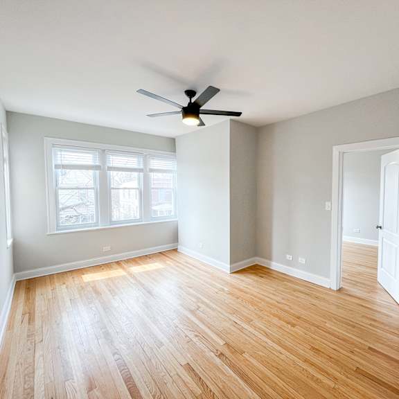 an empty living room with wood floors and a ceiling fan