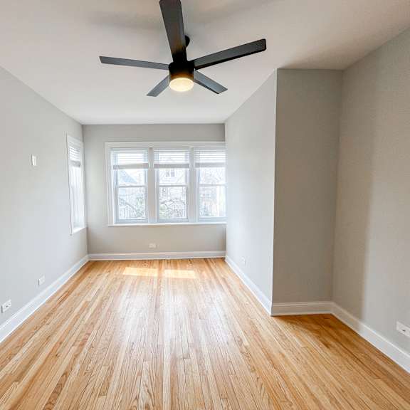 an empty living room with wood floors and a ceiling fan