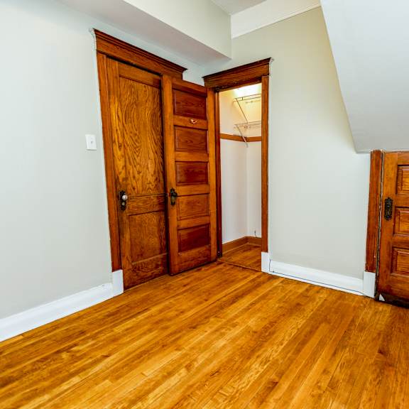 a room with wooden floors and three wooden doors.