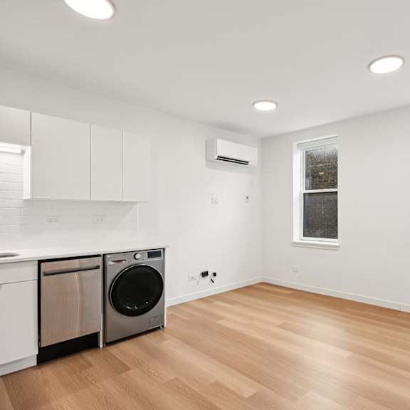 a clean, empty room with a washing machine and a window.