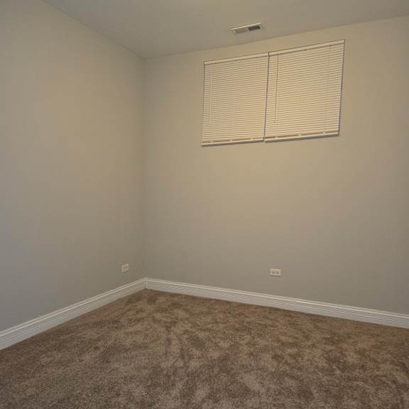 a room with a carpeted floor and a white wall with a light switch.