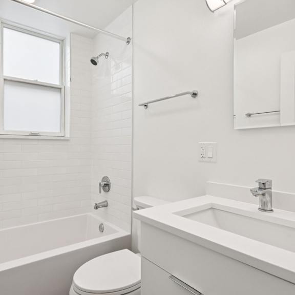 a white bathroom with a toilet, sink, and bathtub.