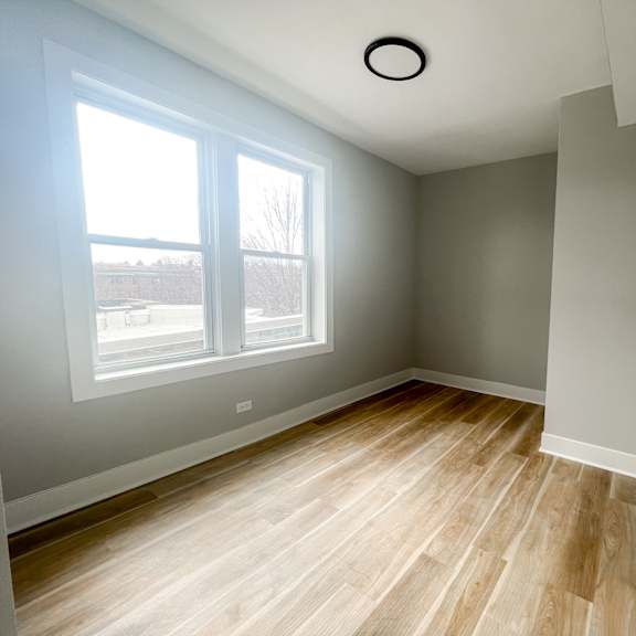 a room with a window and wooden flooring.