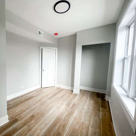 a room with a white door and a window on the right side.
