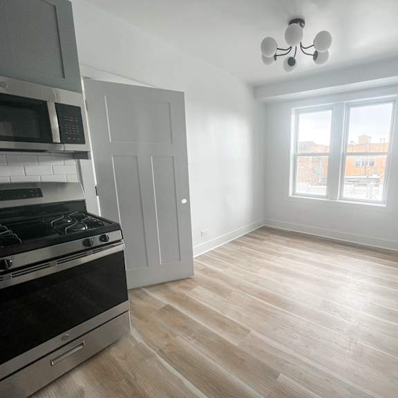a kitchen with a stove, microwave, and a window.