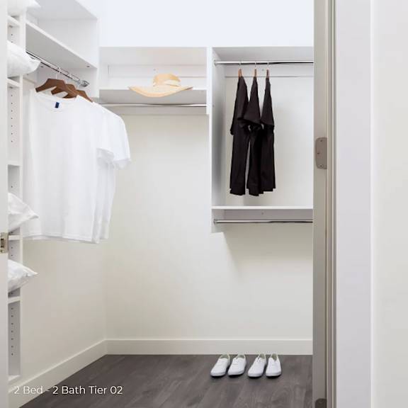 a walk in closet with a closet door open and a closet with clothes hanging