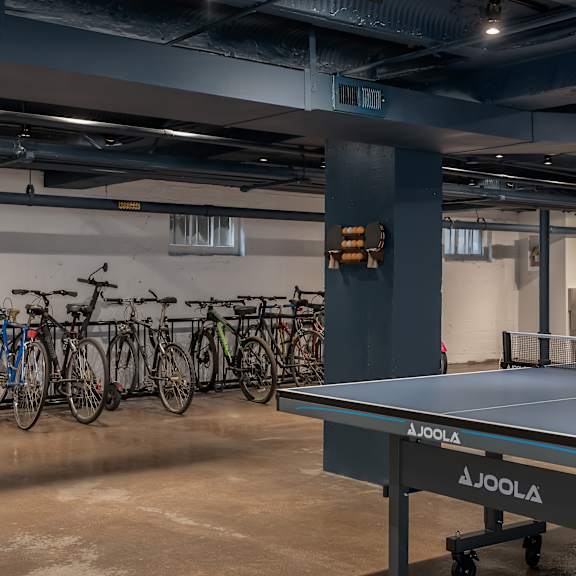 a joola table tennis table is in a basement with bicycles in the background.