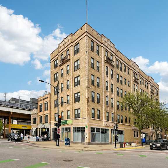 a large tan building with a flat roof and a street in front of it.