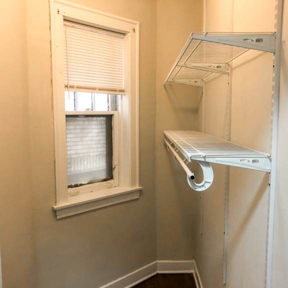 a small white closet with a window and shelves.