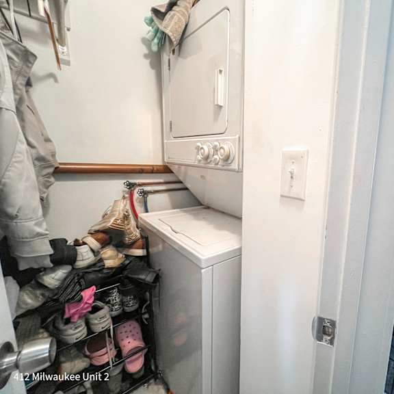 a small laundry room with a washer and dryer, and a basket of shoes.