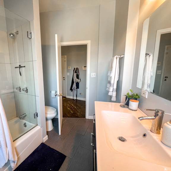 a white towel hangs on a glass shower door in a bathroom.