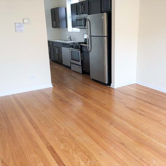 a kitchen and living room with wood floors and a refrigerator