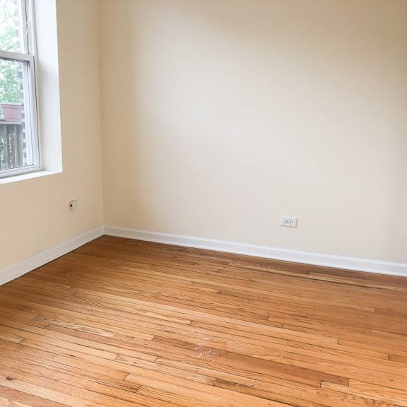 an empty room with wooden flooring and two windows