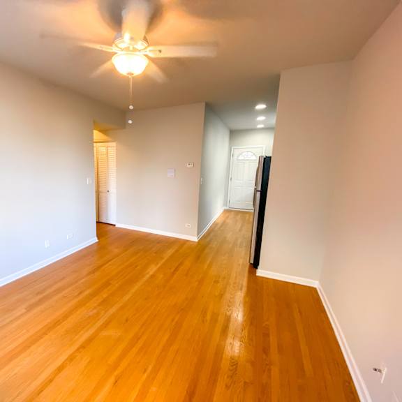 an empty living room with wood floors and a ceiling fan