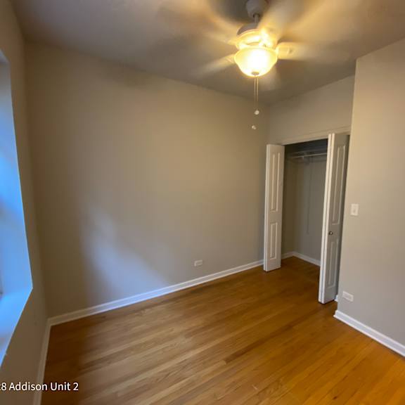 an empty living room with wood floors and a ceiling fan