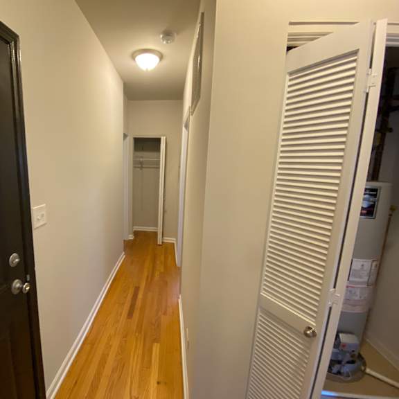 a small hallway with a closet and a door to a hallway with wood flooring