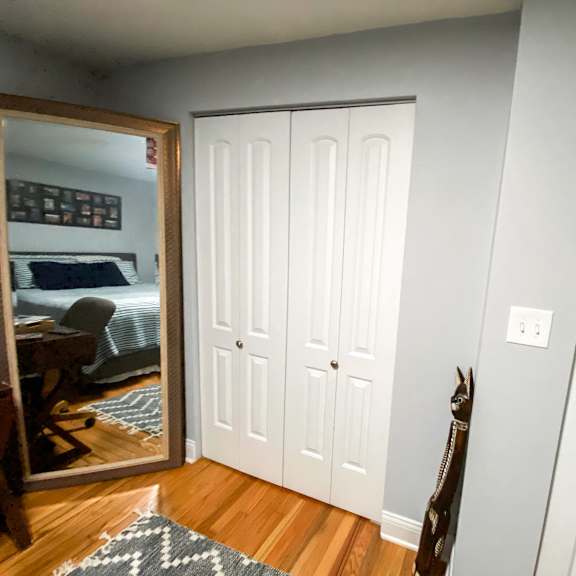 a room with a white door and a mirror on the wall.