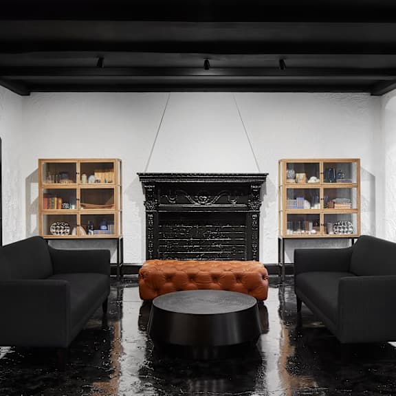 a black couch sits in front of a fireplace in a room with a black floor.