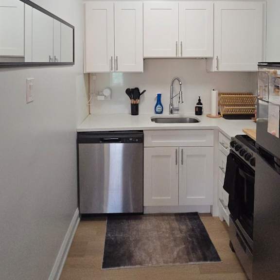 a kitchen with white cabinets and a stainless steel dishwasher.