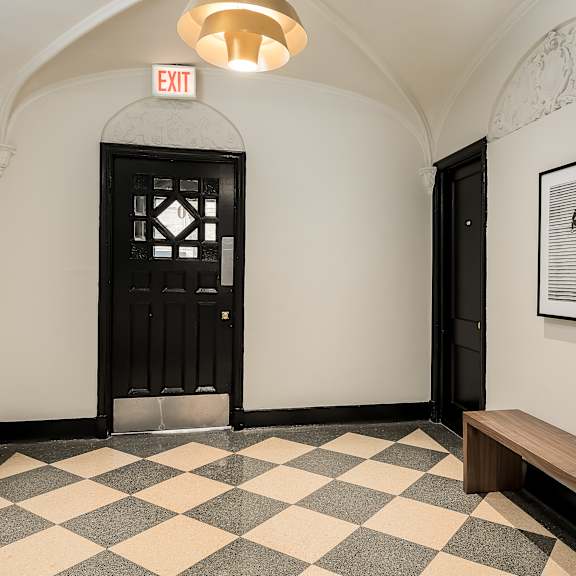 a black door with a window in the middle is flanked by two white walls.