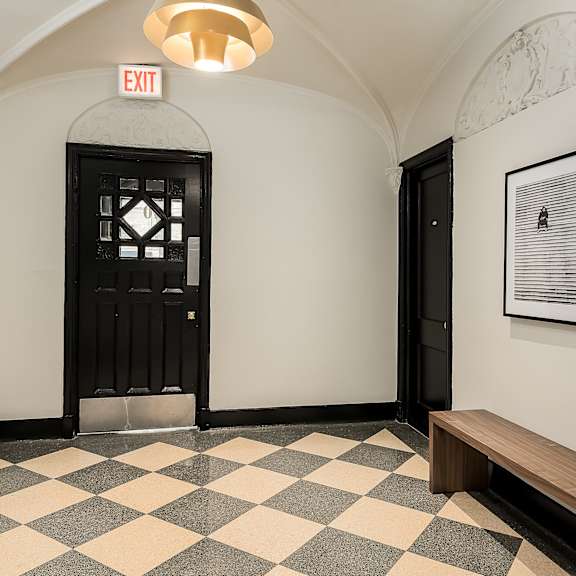 a hallway with a black door and a bench and a checkerboard floor