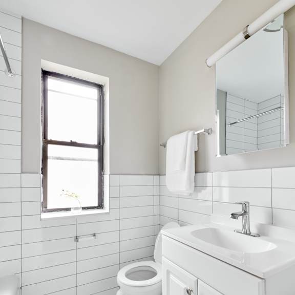 a white bathroom with a toilet, sink, and a window.