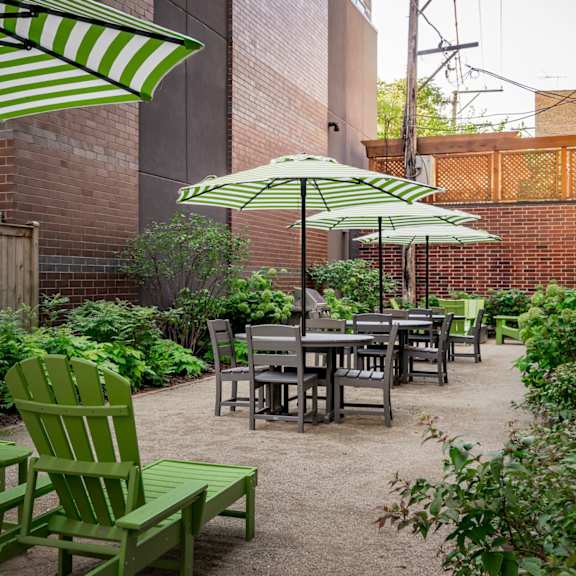 a patio with green chairs and tables.