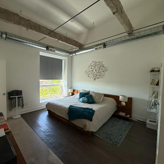 a bedroom with a bed, a window, and a table with books on it.