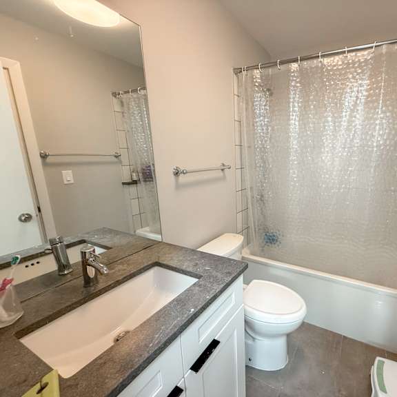 a bathroom with a white toilet, sink, and shower.