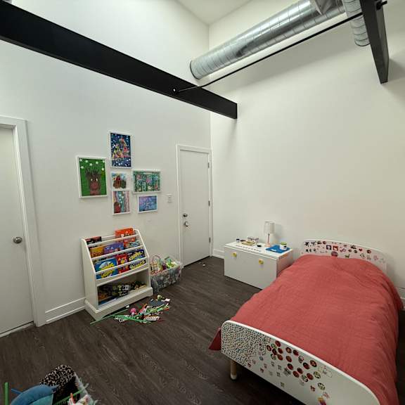 a bedroom with a red bed and a bookshelf filled with books.