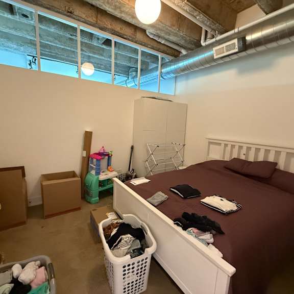 a bedroom with a bed, a basket, and a window.