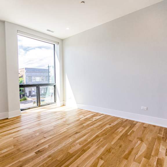 an empty living room with wood flooring and a balcony