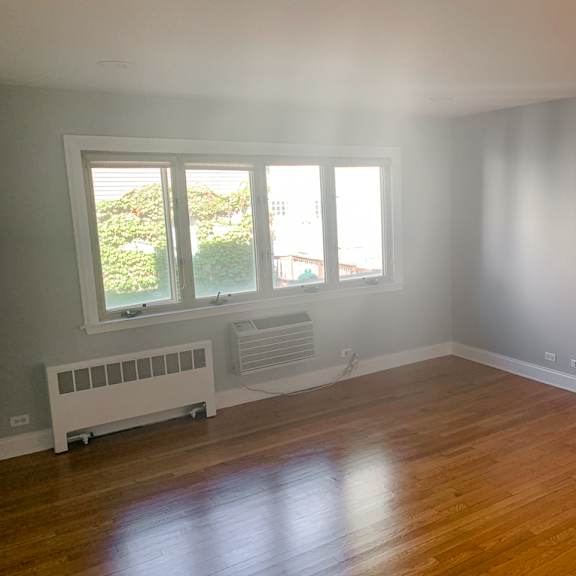 an empty living room with a wooden floor and a window