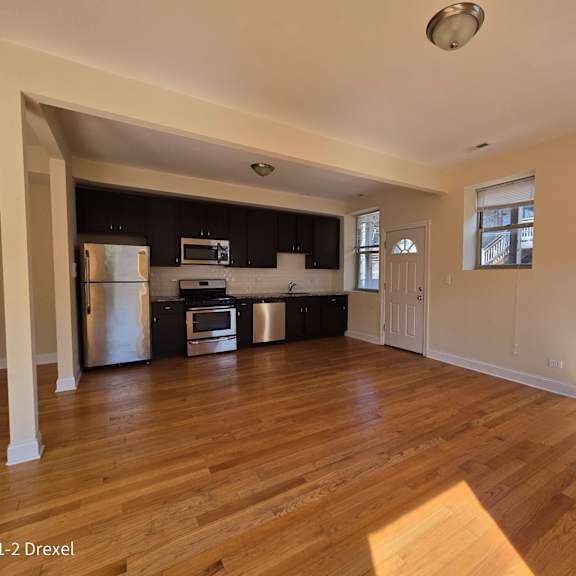 an empty living room and kitchen with wood floors and black cabinets