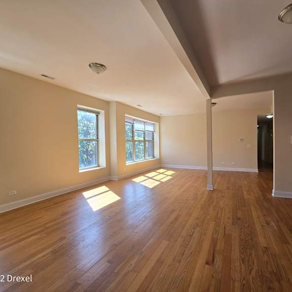 an empty living room with hard wood floors and windows