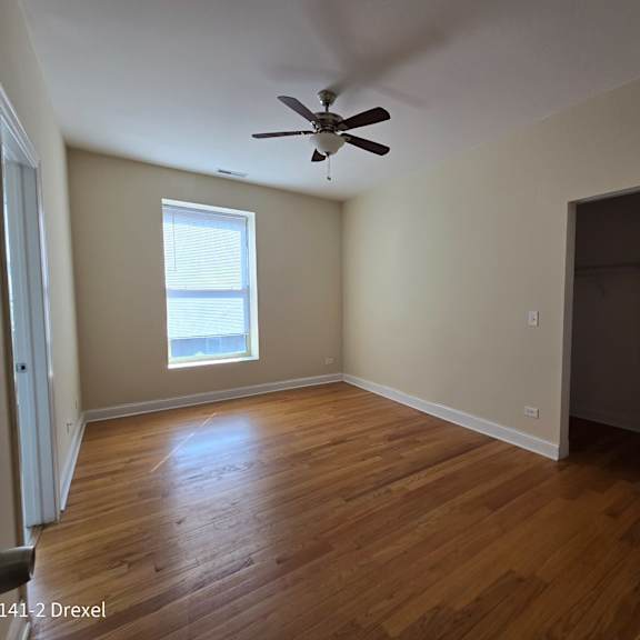 an empty living room with wooden floors and a ceiling fan