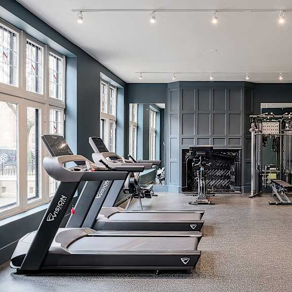 a gym with treadmills, weights, and a bench press.