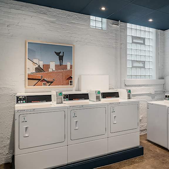 four white washing machines in a room with white cabinets