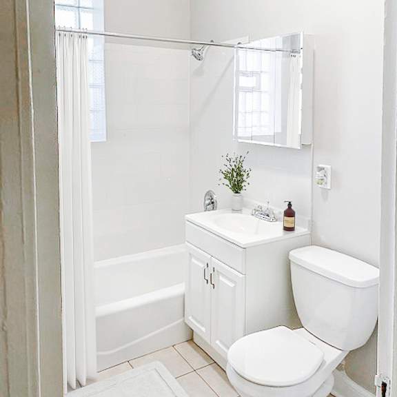 a white bathroom with a toilet, sink, and bathtub.