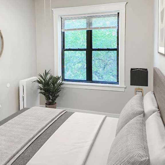 a bedroom with a bed, a ceiling fan, and a window with a plant on the windowsill.