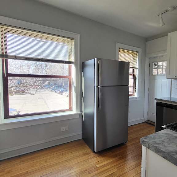 an empty kitchen with a refrigerator and a window
