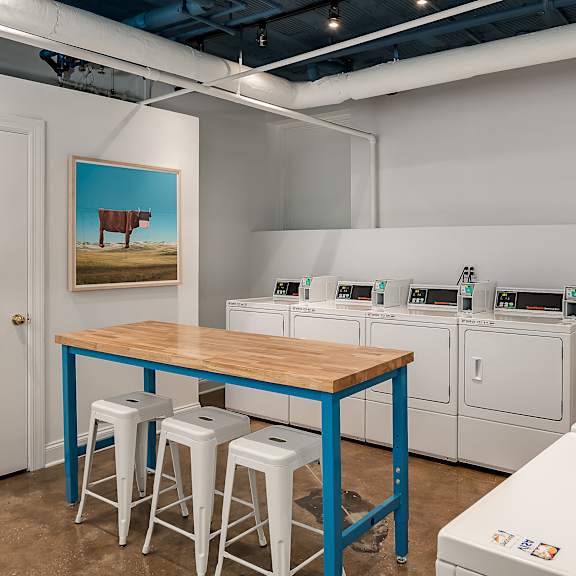 a laundry room with a table and stools and washing machines