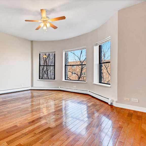 an empty living room with hardwood floors and a ceiling fan