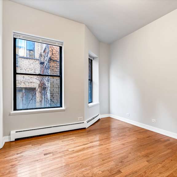an empty living room with wood floors and a window