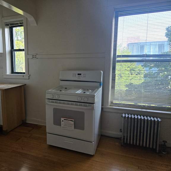 a white oven and stove in a kitchen with wood floors and white walls.