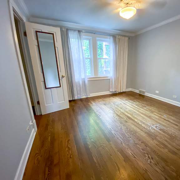 an empty living room with wood floors and a window