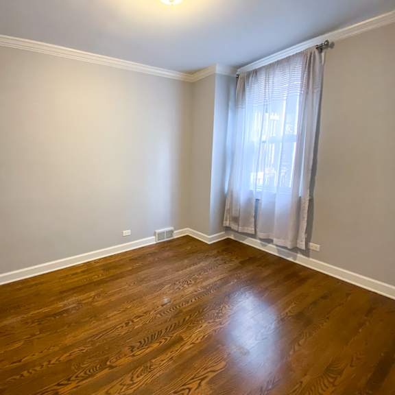 an empty living room with wood floors and a window