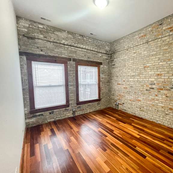 a room with wooden floors and a brick wall.