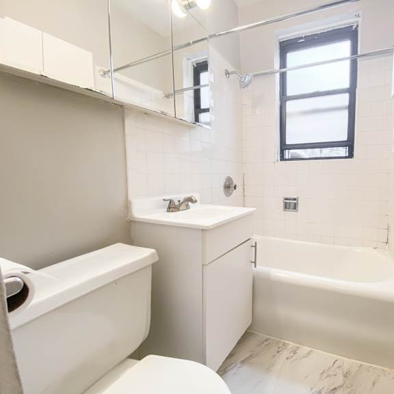 a white bathroom with a toilet, sink, and bathtub.