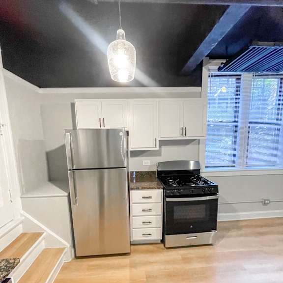 a kitchen with white cabinets and a stainless steel refrigerator